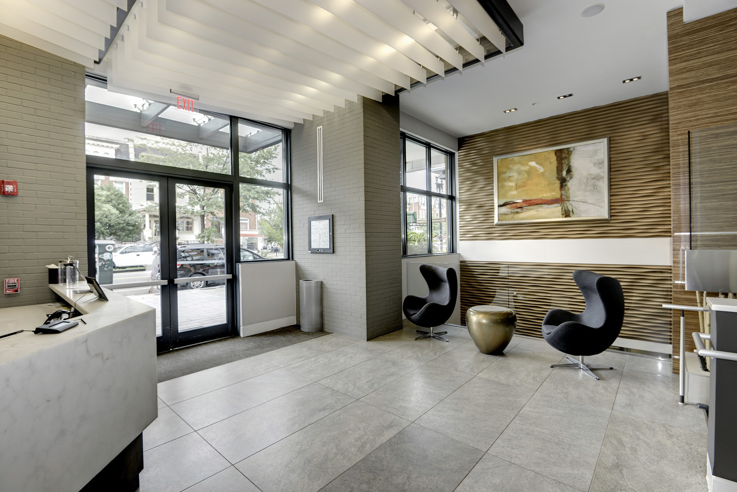 Interior of building entrance with view of modern lobby seating and large abstract art on wood wave wallcovering