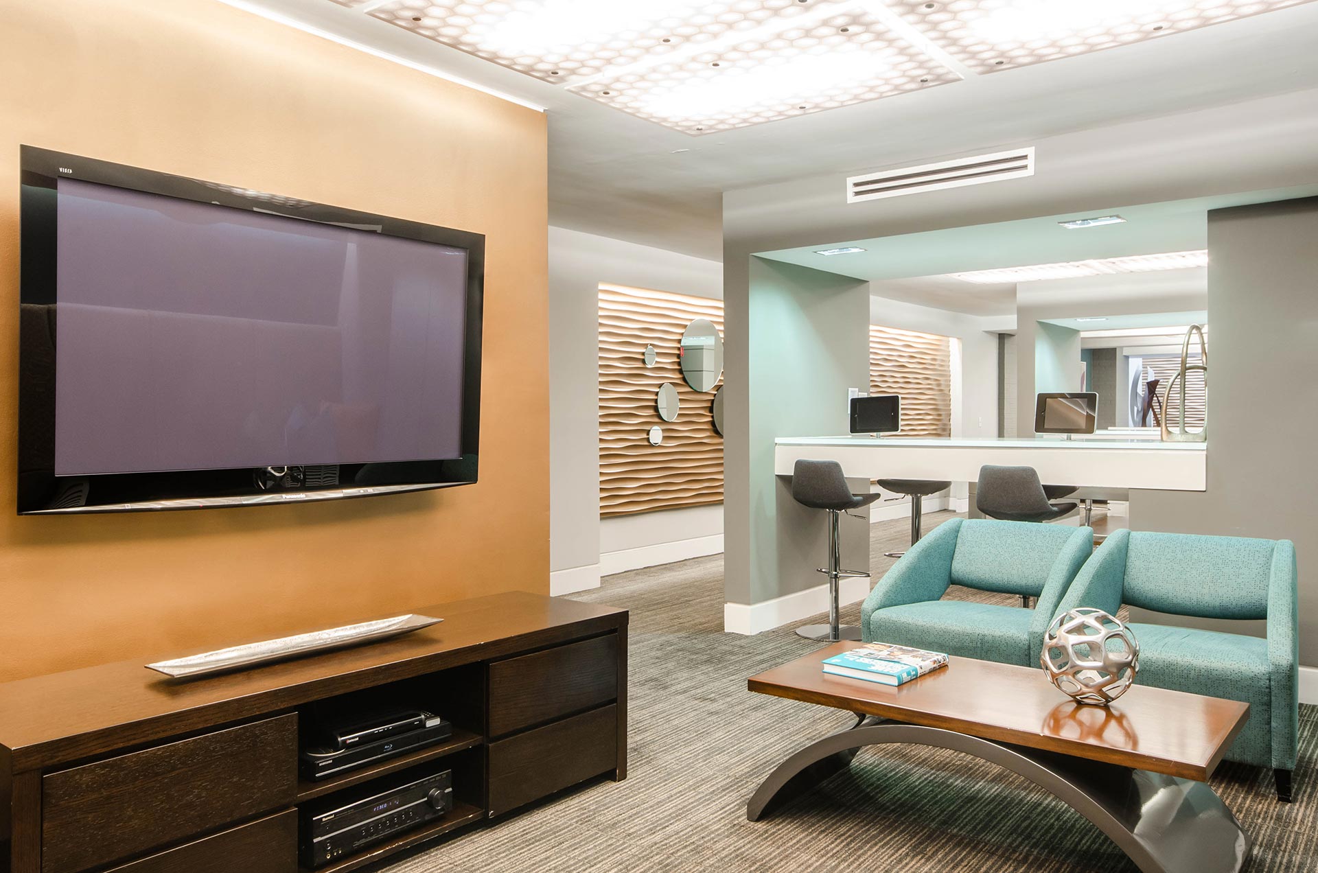 Brightly lit entertainment center with large TV and armchairs