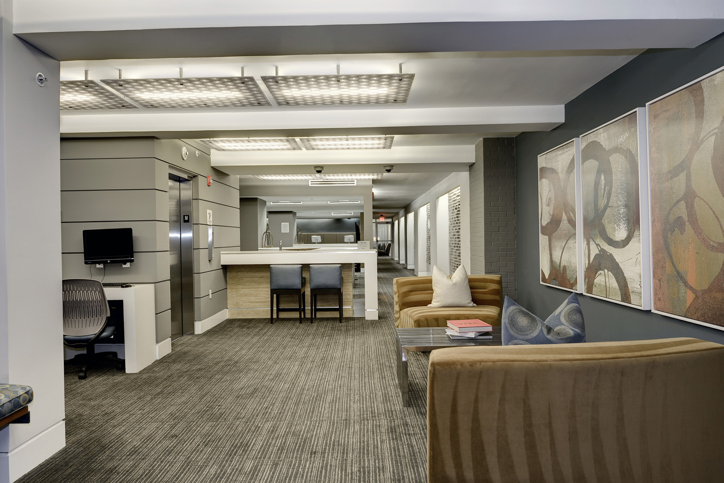 Clubroom hallway with armchairs, abstract art and bar seating in background
