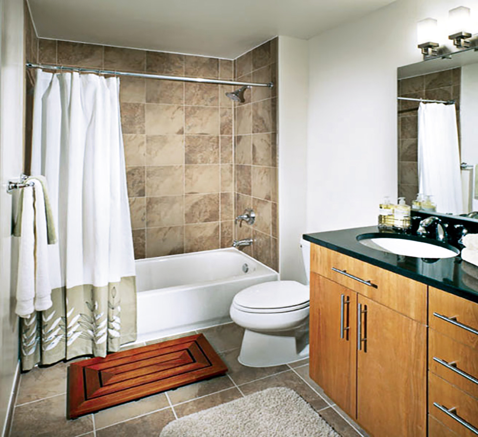 Model unit bathroom with double sink vanity, toiler, and tub shower with large format tiles